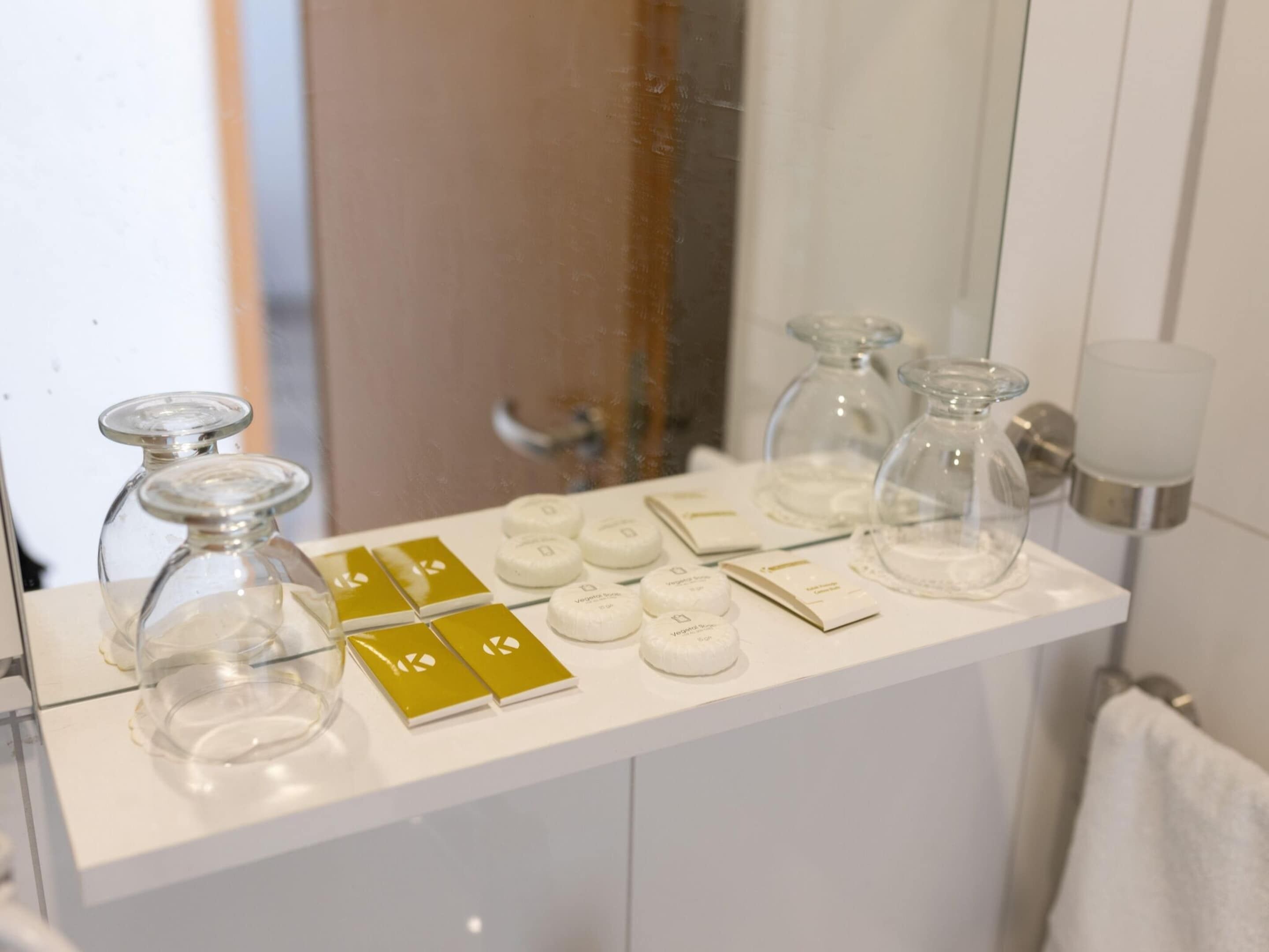 Un meuble-lavabo de salle de bain avec un plan de toilette blanc, des flacons en verre transparent et des distributeurs de savon blancs.