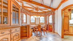 A traditional kitchen with wooden cabinetry, a dining area with a round table and chairs, and large windows with curtains. - Spacious Flat in Adenau Near the Nurburgring (Adenau)