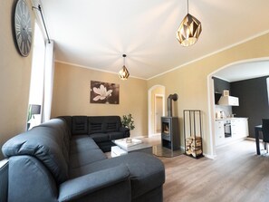 Ein modernes Wohnzimmer mit einer Eckcouch, einem Kamin und einer Küche im Hintergrund.
