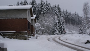 A snow-covered road with a building on the left. - Holiday Home With Garden (Rechenberg-Bienenmuehle)