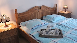 A bedroom with two wooden beds, each with a matching nightstand and lamp. A tray with teapots and cups is placed on the bed. - Wohnung im Teutoburger Wald (Blomberg)