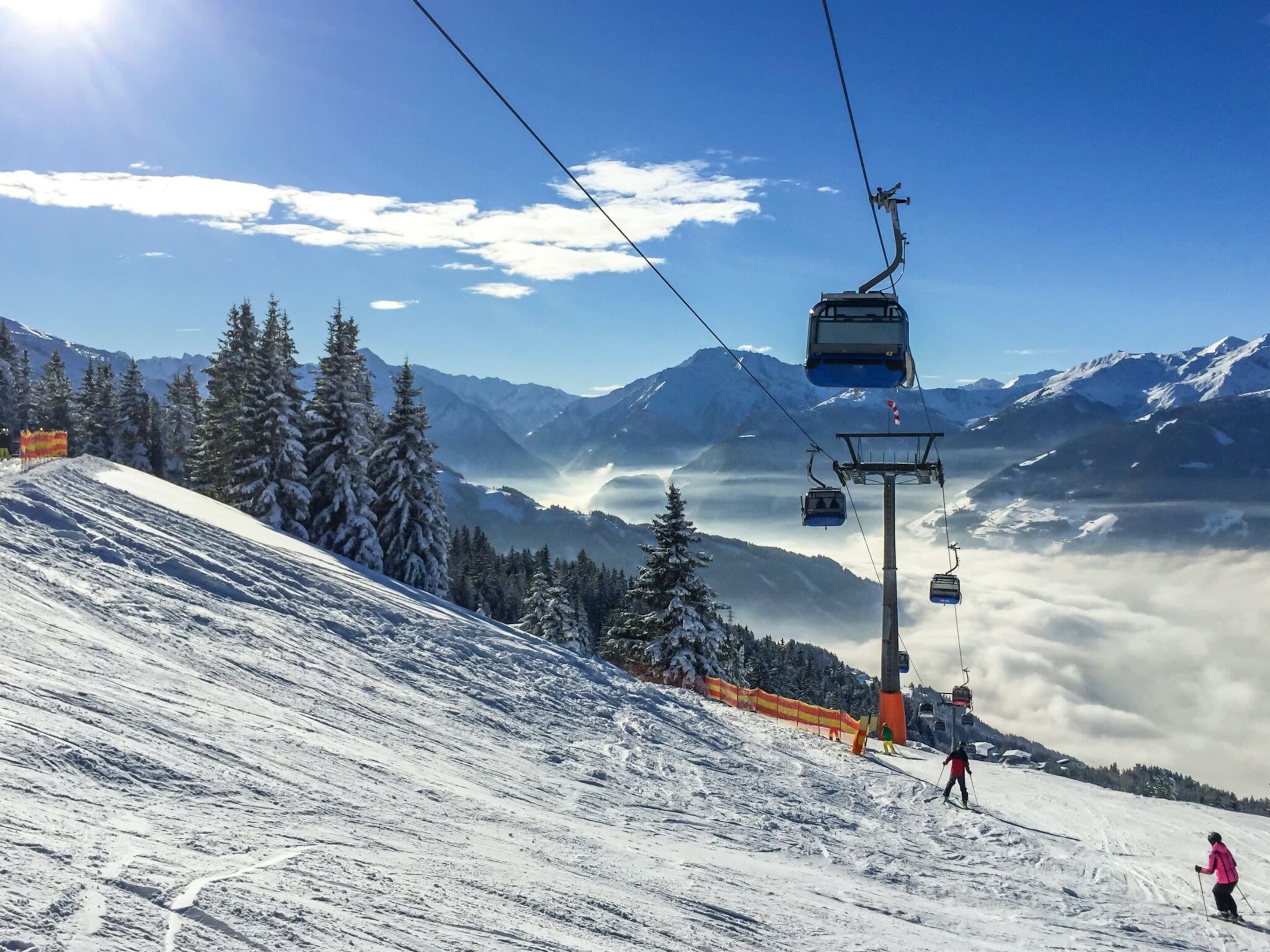 A ski lift with a clear view of snow-covered mountains and trees in the background.