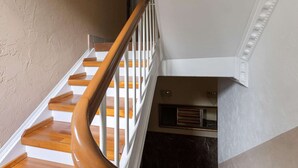 A staircase with wooden steps and white railings, leading to a landing with a dark marble wall and a framed mirror. - Lakeside Base in Oberhausen (Oberhausen)