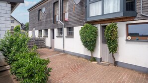 Une maison moderne à deux étages, avec un chemin en briques menant à l’entrée.