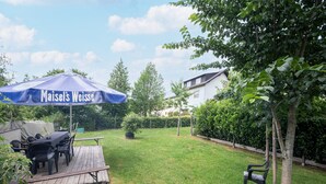Un jardin avec un patio couvert, une table et des chaises.