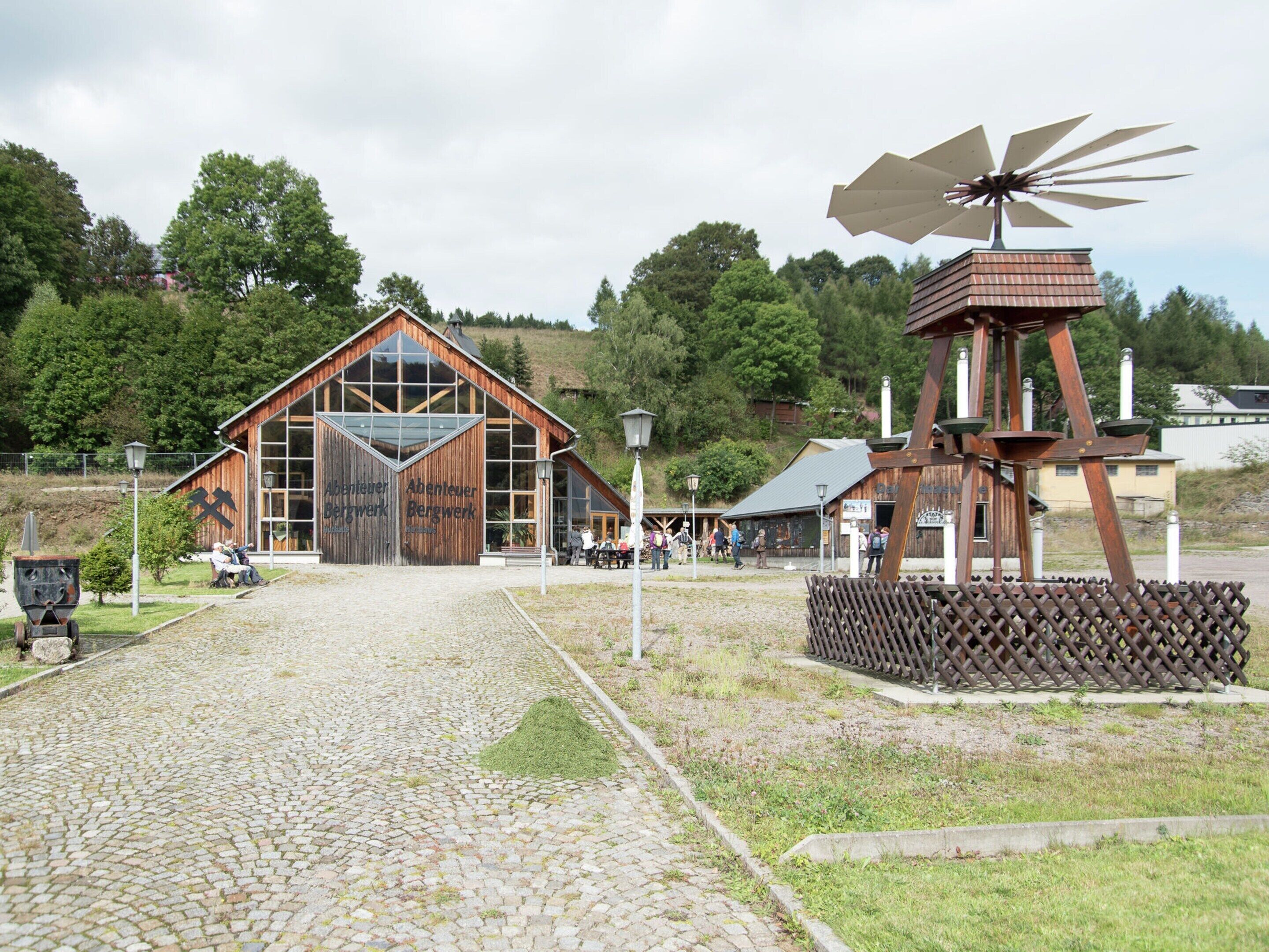 Un bâtiment rustique doté d’une grande façade en bois et d’un moulin à proximité.