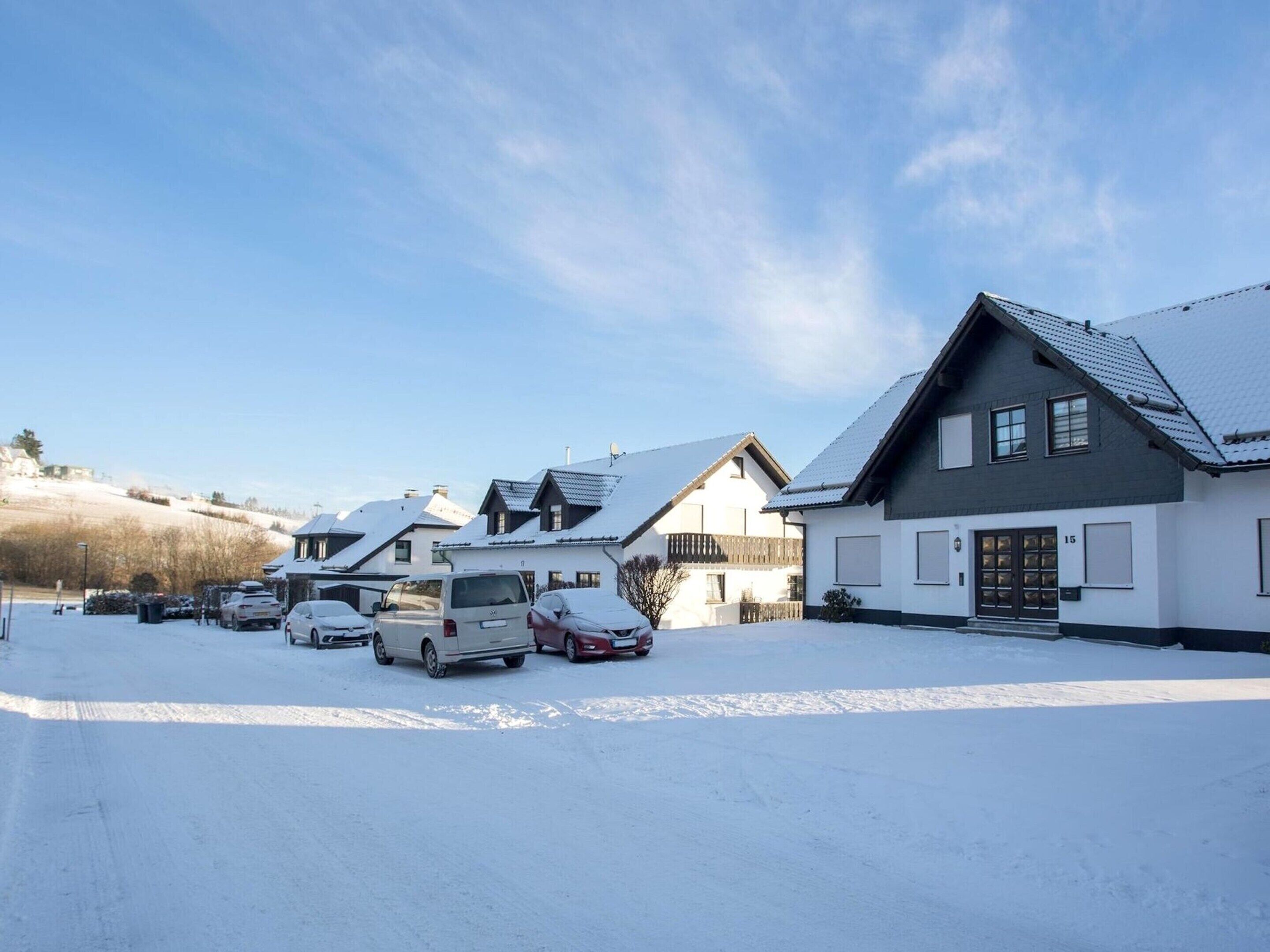 Ett bostadsområde med hus och parkerade bilar, allt täckt av snö.