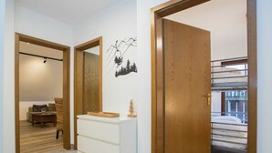 A hallway with a wooden door, a white dresser, and a wall-mounted mirror. - Apartment With Balcony in Neuastenberg (Winterberg)