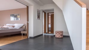 A modern bedroom with a bed, a small bedside table, and a nightstand. There is a door leading to another room. - Elegant Escape in Quedlinburg (Quedlinburg)