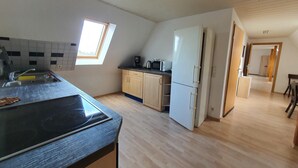 A kitchen with a skylight, wooden cabinets, a white refrigerator, and a black countertop.