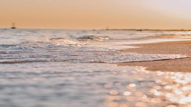 A beach scene with waves gently lapping onto the shore. - Wellness & Comfort Retreat (Fehmarn)