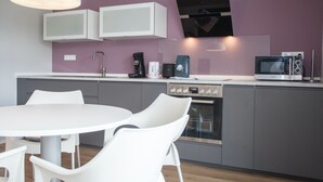 A modern kitchen with white cabinets, a built-in oven, a microwave, and a coffee maker. - Apartment With Terrace Near Niedersfeld Forest (Winterberg)