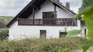 A white building with a sloped roof, wooden balcony, and chimneys. - Apartment With Terrace Near Niedersfeld Forest (Winterberg)