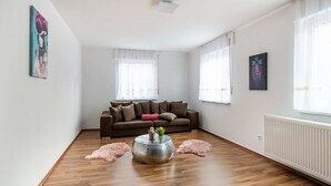 Ein geräumiges Wohnzimmer mit einem braunen Sofa, einem runden Couchtisch und einem flauschigen Teppich.