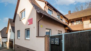 Ein zweistöckiges Haus mit geneigtem Dach, einem sichtbaren Briefkasten und einem Schild, das auf ein Geschäft hinweist.