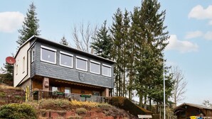 A modern two-story house with a sloped roof, large windows, and a stone retaining wall. - Ferienhaus in Harzgerode (Harzgerode)
