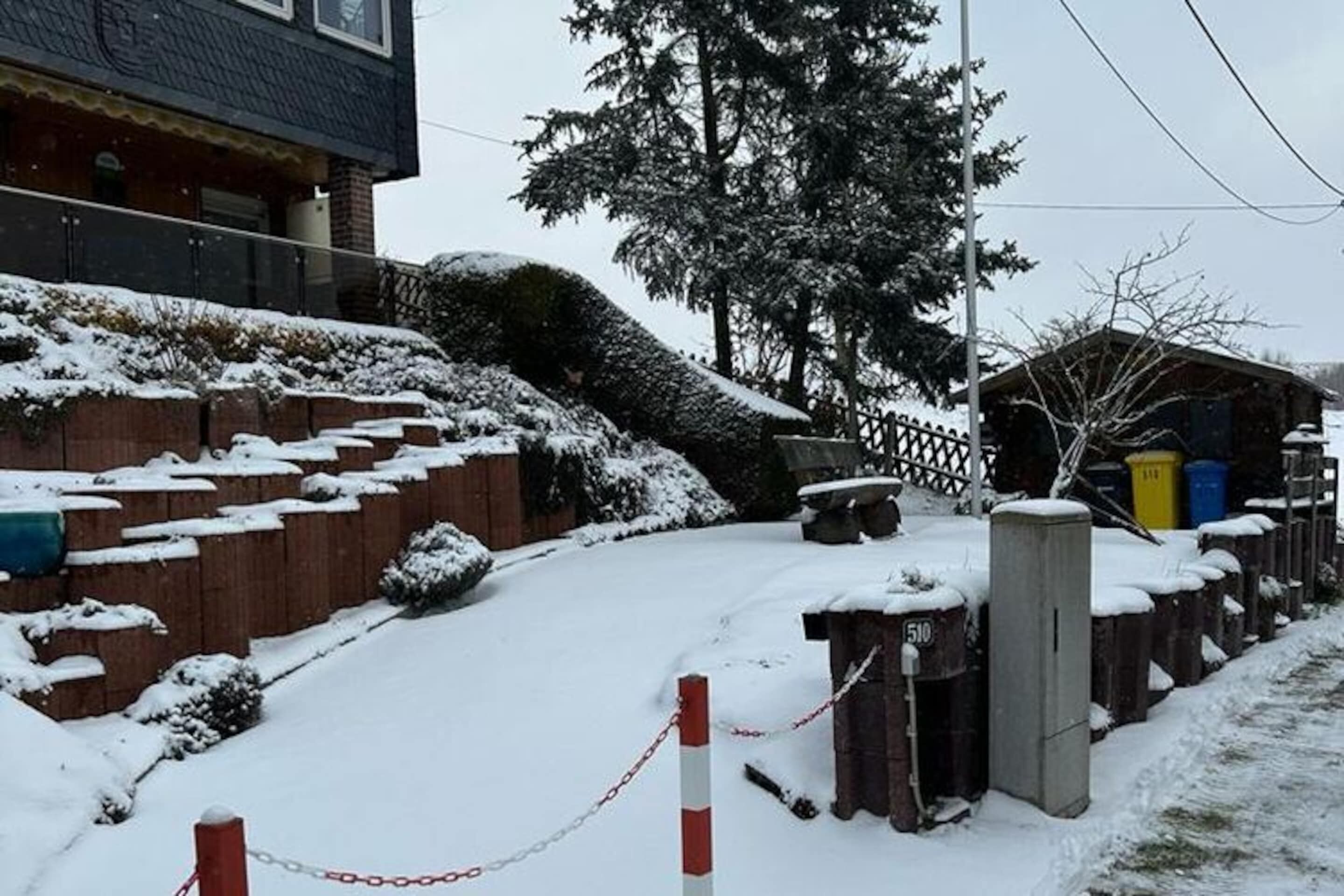 Área externa coberta de neve, com cerca de madeira, um pequeno galpão e uma caixa de utilidades com o número 510.