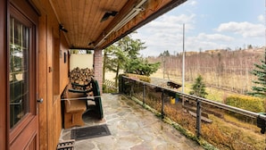 A wooden porch with a stone floor, a bench, and a stack of firewood. - Ferienhaus in Harzgerode (Harzgerode)