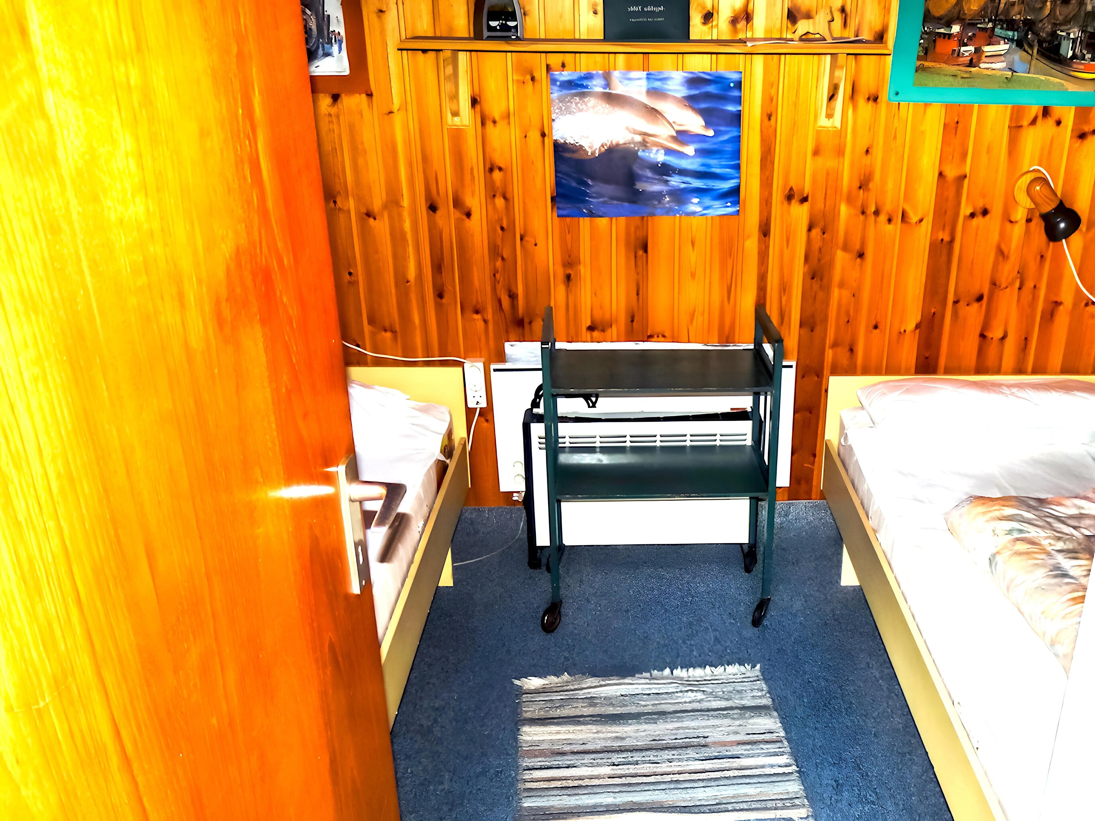 Une pièce en bois avec un lit, un bureau et un téléviseur fixé au mur.