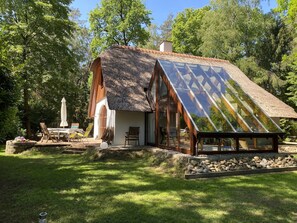 Escape to a serene cottage nestled in a lush garden with a spacious interior and outdoor seating area.