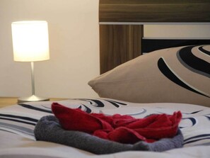A neatly made bed with a patterned bedspread, a red towel, and a lamp on a bedside table. - Grosszugiger Komfort, Rubeland (Oberharz am Brocken)