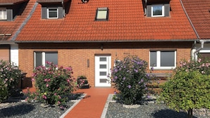 A two-story building with a red-tiled roof, a brick facade, and a central entrance with a white door. - Grosszugiger Komfort, Rubeland (Oberharz am Brocken)