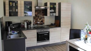 A modern kitchen with light wood cabinets, a stainless steel range hood, and a built-in oven. - Grosszugiger Komfort, Rubeland (Oberharz am Brocken)