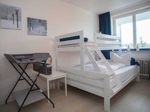 A bunk bed room with a small table and chair, a radiator, and a window with curtains. - Apartment in Winterberg With Balcony (Winterberg)