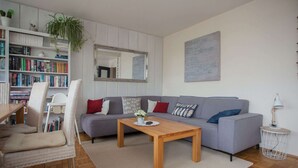 A modern living room with a grey sofa, a wooden coffee table, and a bookshelf filled with books. - Apartment in Winterberg With Balcony (Winterberg)