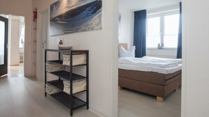 A bedroom with a bed, a shelf with storage bins, a painting of a mountain landscape, and a window with curtains. - Apartment in Winterberg With Balcony (Winterberg)