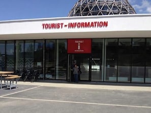 En turistinformation med en modern design, kännetecknad av stora glasfönster och en framträdande kupolformad byggnad.