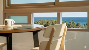 A room with a round table, a white chair, and a view of the sea through large windows. - Sokcho Pensionbyeol (Sokcho)