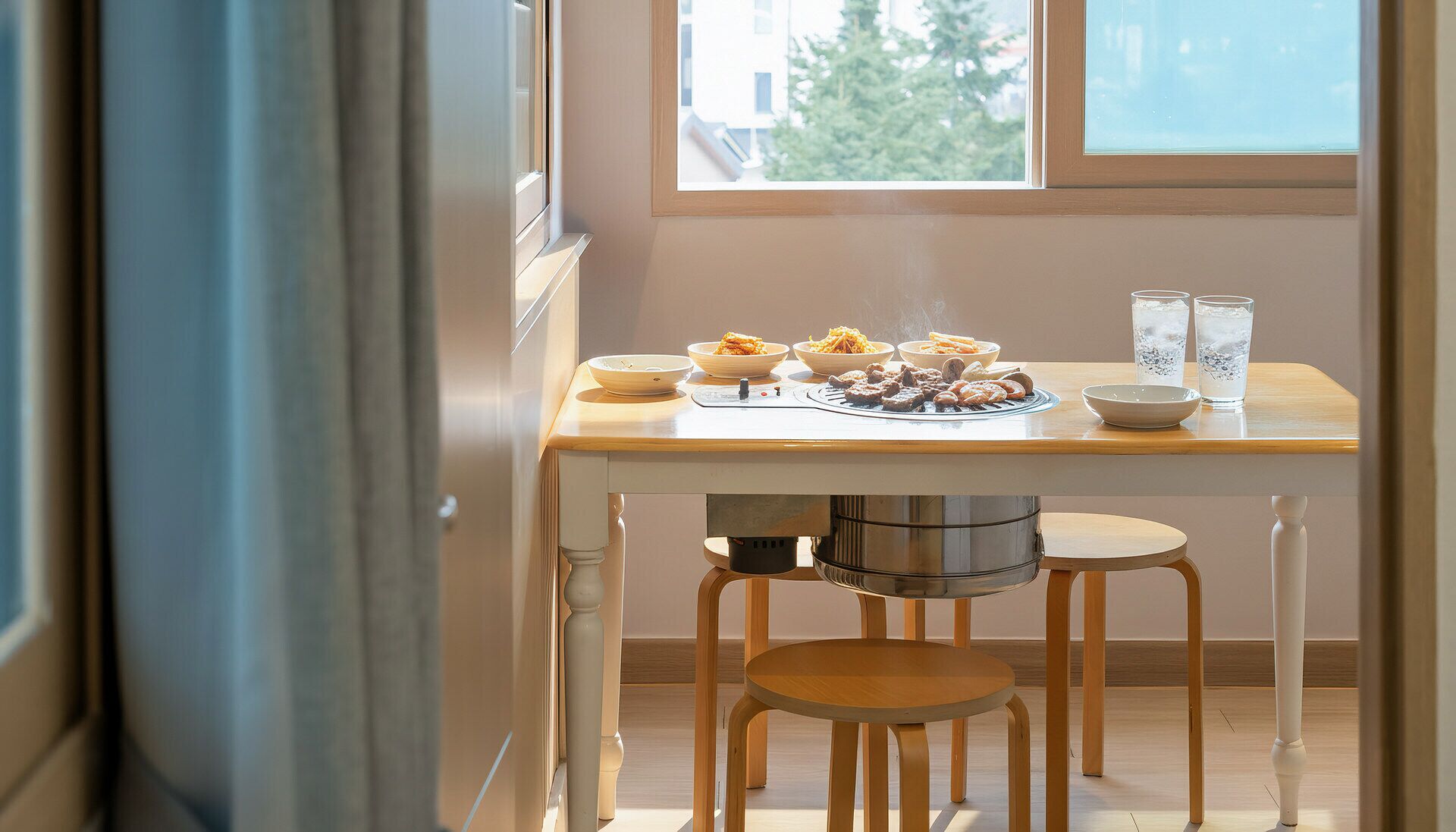 A dining area with a table set for a meal, a grill, and two glasses of water.