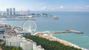 A coastal cityscape with a prominent Ferris wheel, a beach, and a lighthouse. - Sokcho Pensionbyeol (Sokcho)