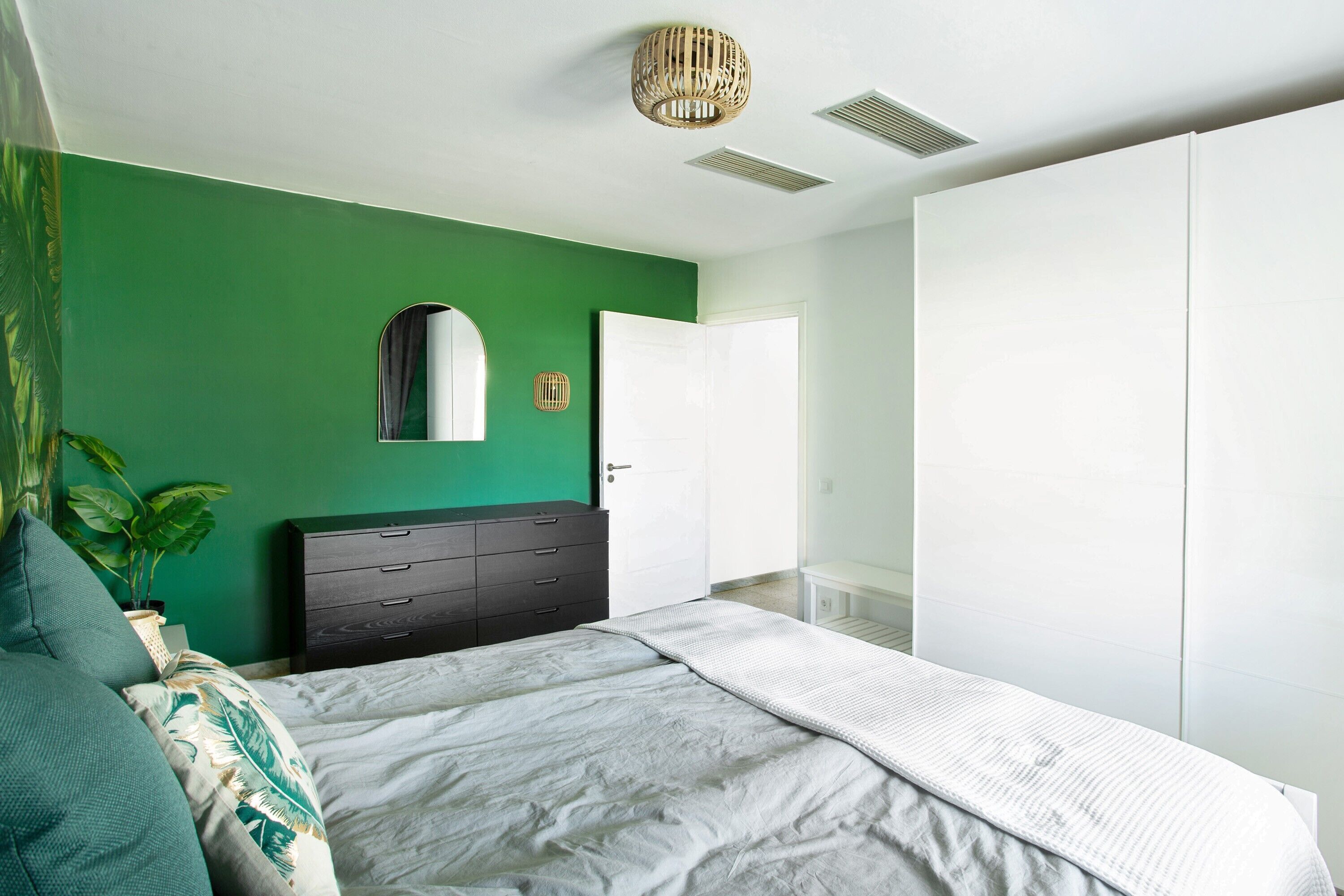 Une chambre à coucher comprenant un lit, une commode, un miroir et une armoire.