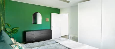 A bedroom with a bed, a dresser, a mirror, and a wardrobe.