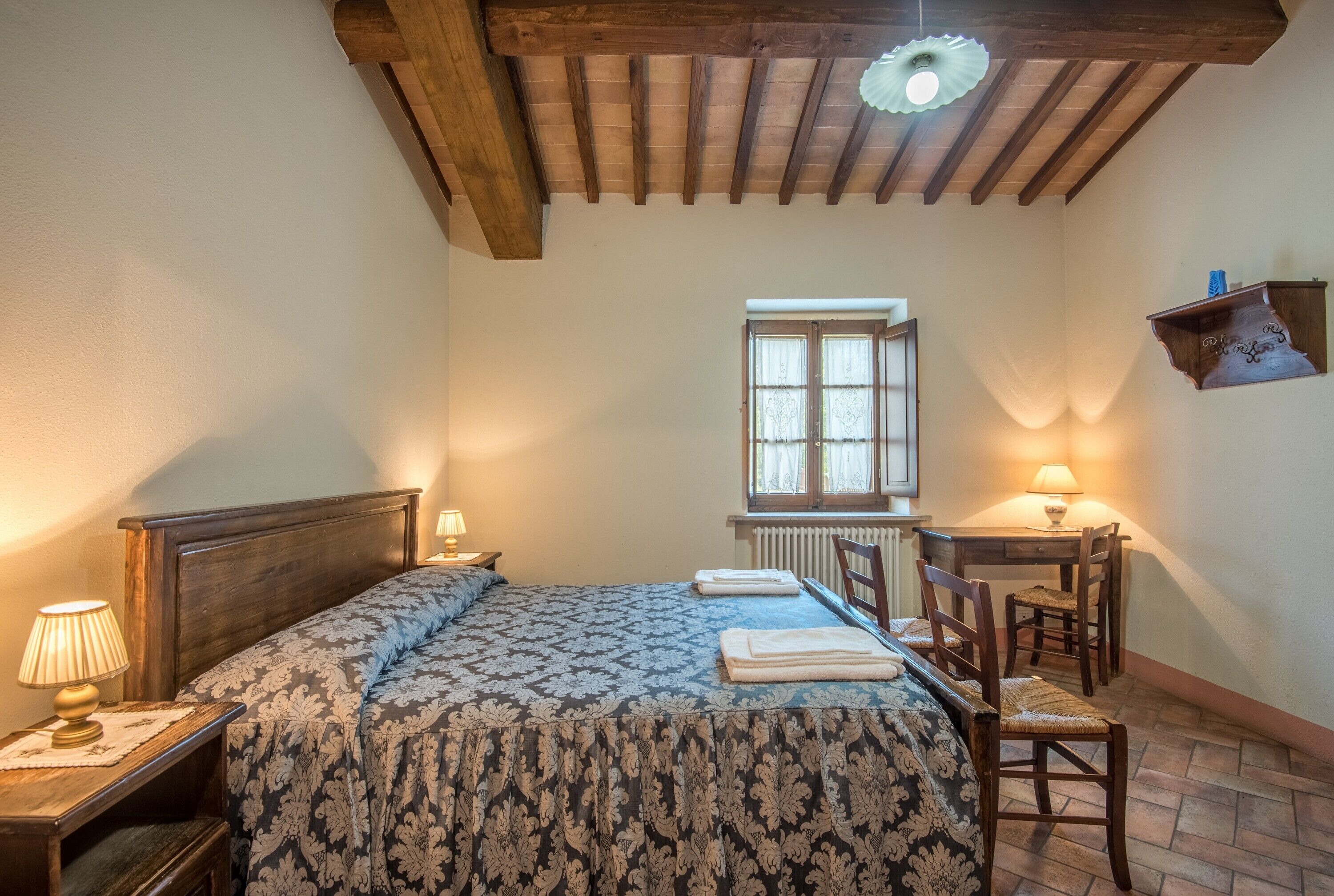 Une chambre à coucher avec un lit en bois, un bureau, une chaise, une fenêtre et un radiateur.