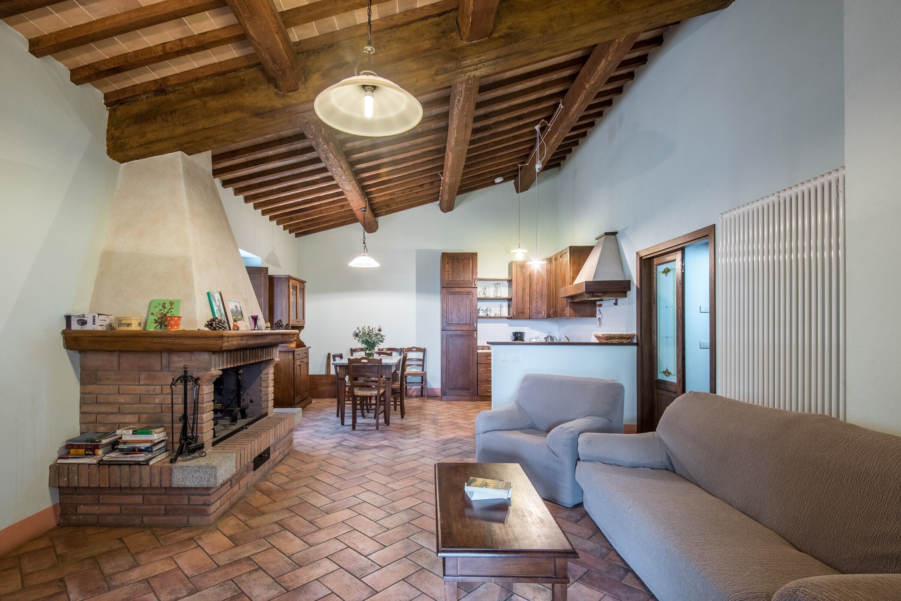 A living room with a fireplace, a sofa, a dining table, and kitchen cabinets.