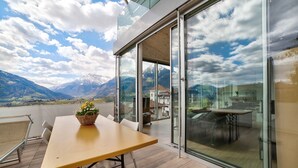 A balcony with a wooden table, chairs, and a basket of flowers. - Apartment 'Villa Alvarium Eins' with Mountain View, Private Terrace and Wi-Fi (Scena)