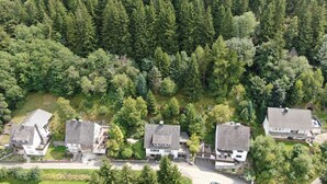 An aerial view of a residential area with houses surrounded by dense forest.