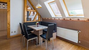 Un coin repas accueillant, avec une table et des chaises, un plafond en bois et une vue à travers une lucarne.