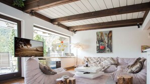 A modern living room with a sofa, coffee table, and a TV mounted on the wall. - Modern Ferienhaus Nahe von Winterberg mit Garten (Winterberg)
