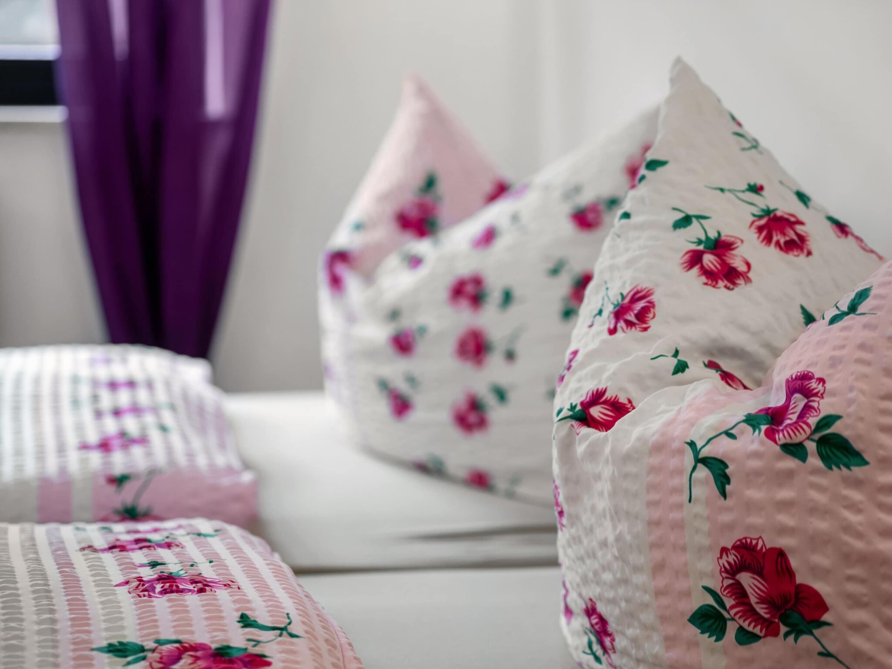 Ein Bett mit blumigem Kissenbezug und einer karierten Tagesdecke.
