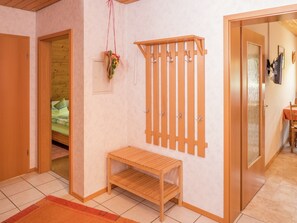 Une pièce avec un banc en bois, un porte-manteau fixé au mur et une plante suspendue.