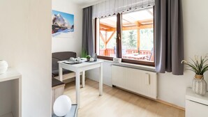 Une pièce moderne et bien éclairée, comprenant une table à manger, un canapé et donnant sur une terrasse extérieure.