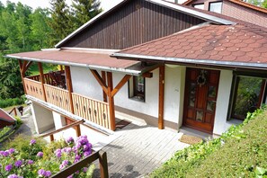 Ein zweistöckiges Haus mit Balkon, Hollerker und einem Ziegeldach.