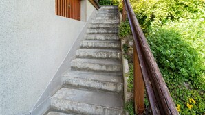 Un escalier en béton menant à un bâtiment, avec une main courante en bois.