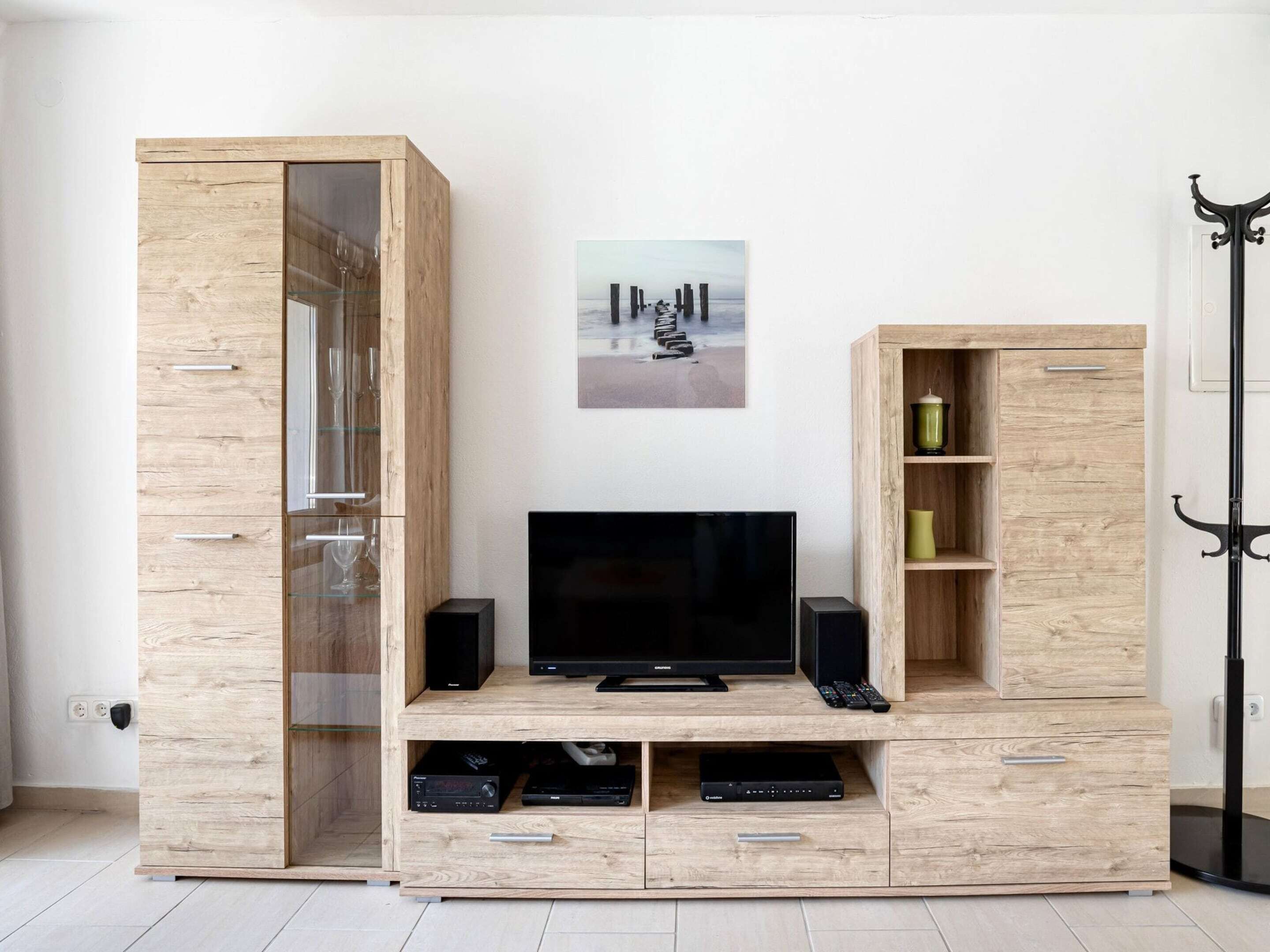 A modern living room with a wooden entertainment unit housing a flat-screen TV, speakers, and a DVD player.