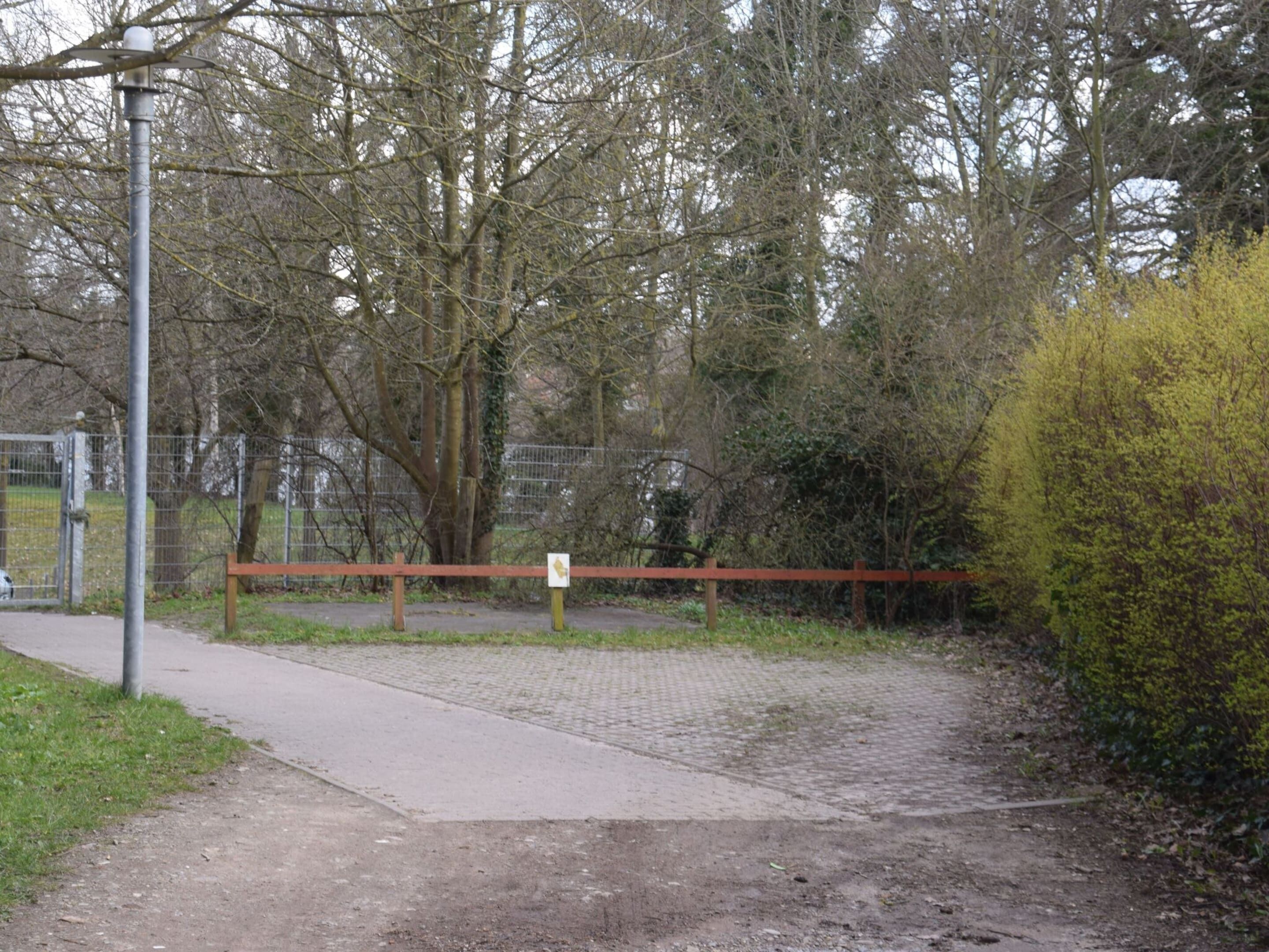 A gated entrance to a park with a paved path leading through it.