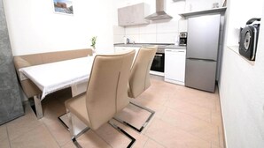 A compact kitchen with modern appliances, a dining area with a table and chairs, and a small kitchenette. - Apartment on a Farm Near Dusseldorf (Juechen)